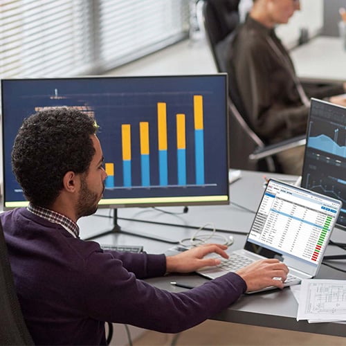 Man sits in front of laptop and analyzes table.