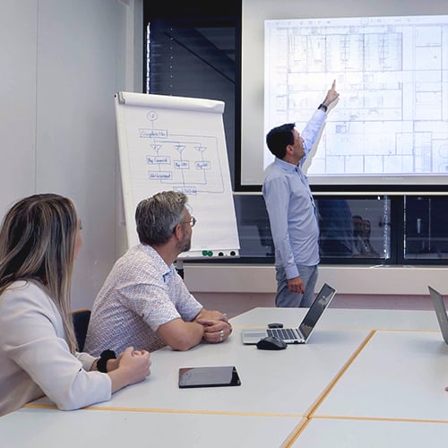Project manager explains a layout plan to his team on the screen.